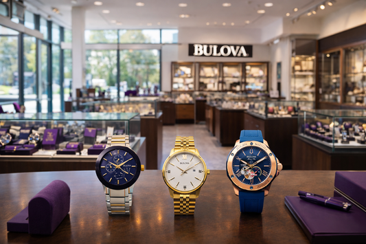 Bulova watch collection displayed in a retail showroom with multiple models on a table.