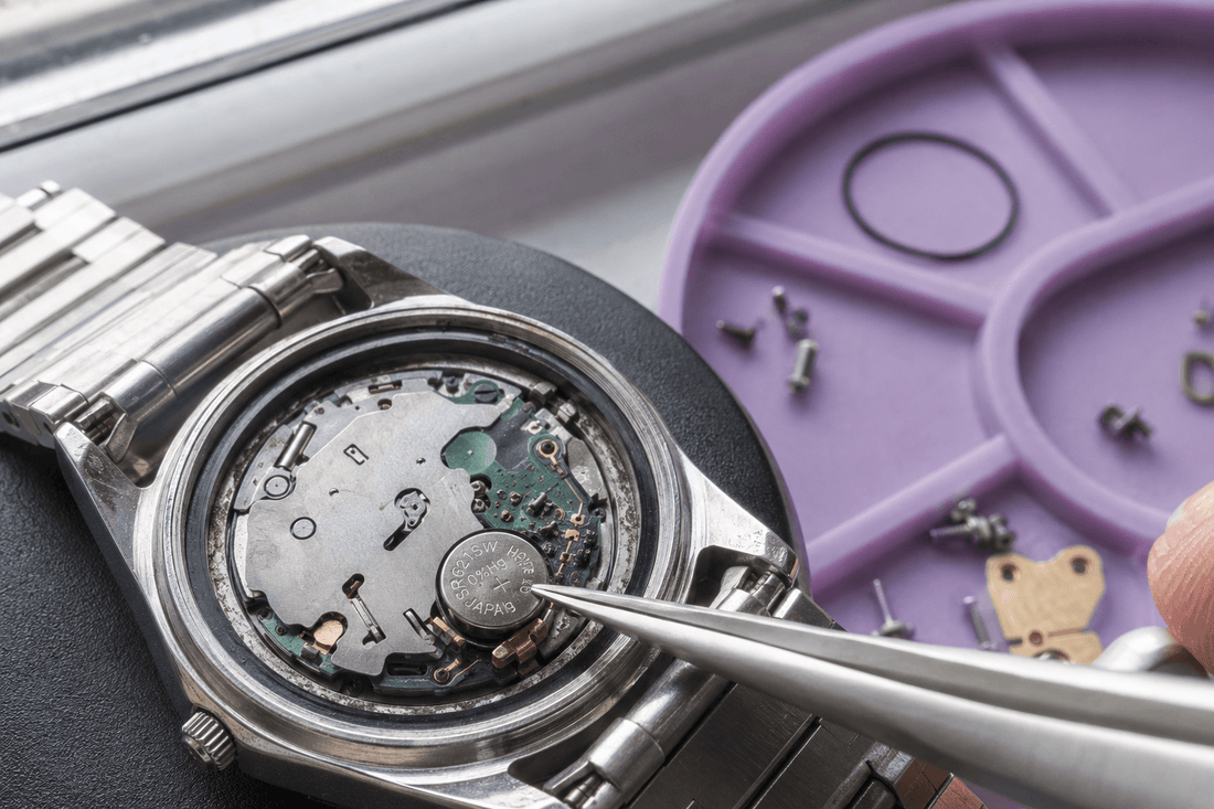 Watchmaker replacing a quartz watch battery with precision tweezers