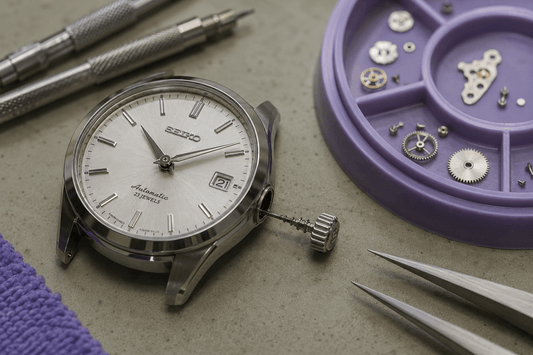 Luxury watch prepared for movement inspection with tools and components nearby.