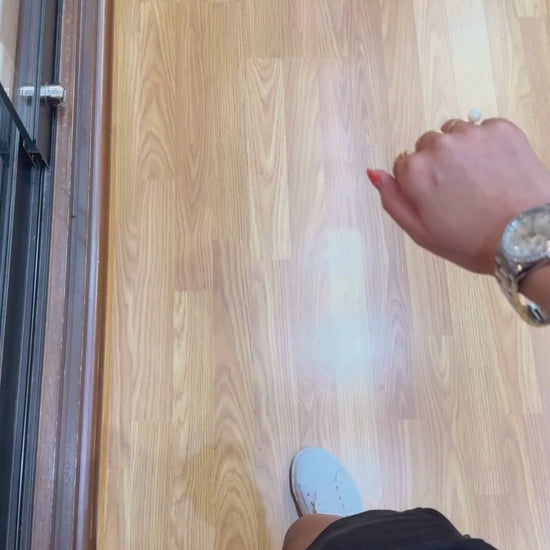 Rolex Datejust with diamond bezel worn on wrist, shown with gold jewelry over wood floor.