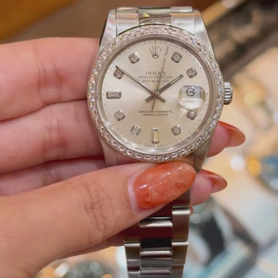 Hand holding a Rolex Datejust with diamond bezel and markers, showcased above a watch tray.